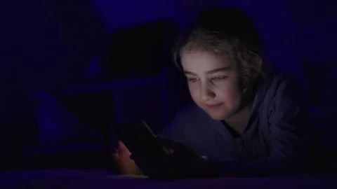 Child Using Mobile Phone Evening at Home. Teen Girl Watching Online Video S.. Stock Footage 329447515