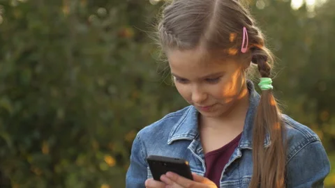 Child is using mobile phone. Kid is looking at screen of devices. Little girl is Stock Footage 125800379