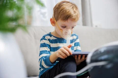 Child Using Nebulizer While Engaged with Tablet at Home Stock Photos