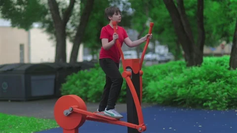 Child Using Outdoor Elliptical Exercise Machine in Park Stockbeeldmateriaal 338013836