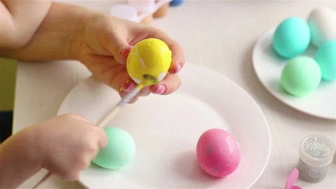 Child using paintrush coloring it with yellow paint  happy easter decoration Stock Footage 147862536