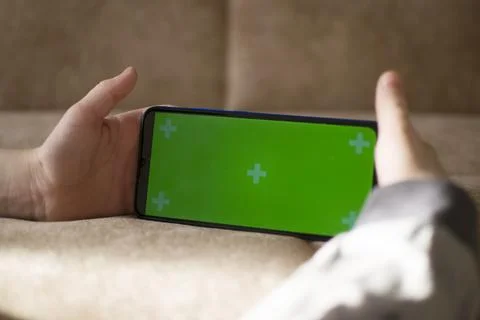 A child is using a phone with a chroma key screen mockup. Stock Photos