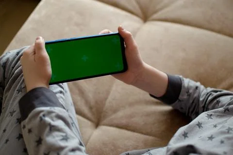 A child is using a phone with a chroma key screen mockup. Stock Photos
