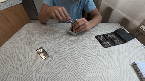 Child using precision screwdriver to repair small electronic device. Close-up of Stock Footage 316143685