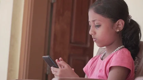 Child Using Smartphone Sending Messages to Friends Girl Playing Games smiling Video stock 128502430