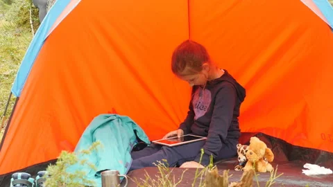 Child using tablet computer outdoor. Little girl playing on tablet pc in camping 動画素材 108055095