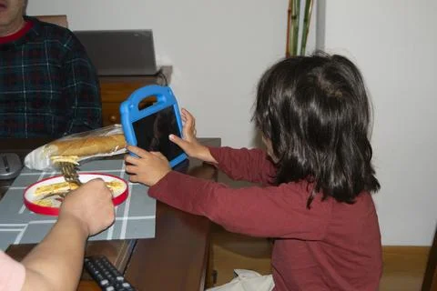 Child using tablet during breakfast with family at home Stock Photos
