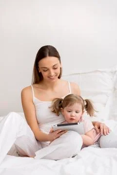 Child using tablet with her mother Stock Photos