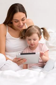 Child using tablet with her mother Stock Photos