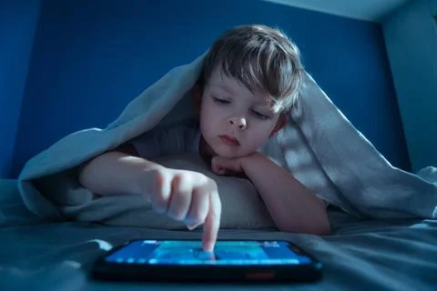 Child using tablet or smartphone at night Stock Photos