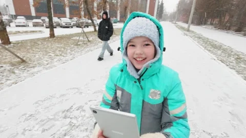 Child Using Tablet While Walking Through Snowy Neighborhood Stock Footage 297701989