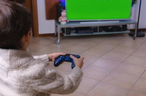Child using technology. The boy sits on the couch, holds a game joystick and Stock Photos