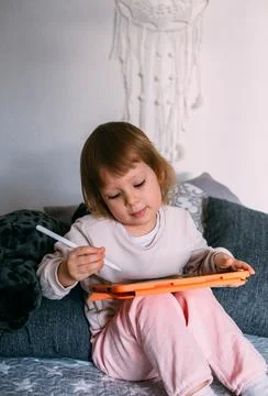 Child using technology. Toddler at home with a tablet and a pen stylus and draws Фото