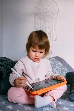 Child using technology. Toddler at home with a tablet and a pen stylus and draws Stock Photos