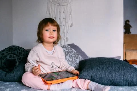 Child using technology. Toddler at home with a tablet and a pen stylus and draws Stock Photos