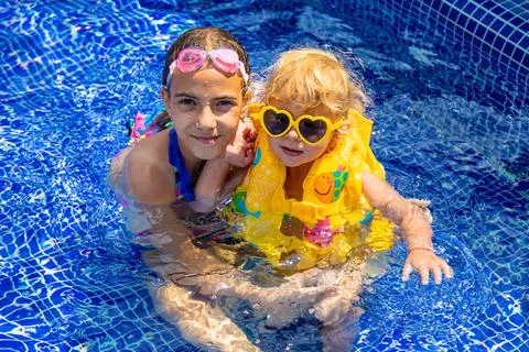 A child in a vest swims in the pool. Selective focus. Stock Photos