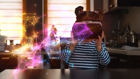 Child with virtual reality headset sitting behind table indoors at home Видео 105341126