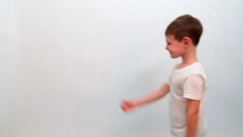 Child walking against a white studio background. Young boy moving forward with Stock Footage 337420158