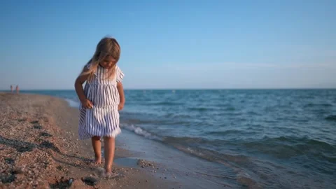 Child walking along the beach at sunset Видео 341120162
