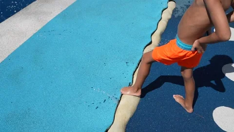 Child Walking Barefoot on Blue Poolside Surface in Orange Swim Shorts Vídeo Stock 347747511