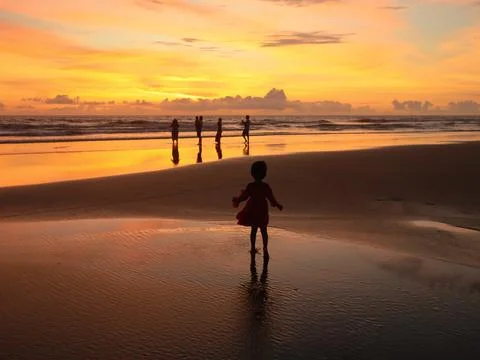 Child walking on the beach at sunset Stock Photos