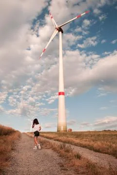 Child walking on the field with windmill. Stock Photos