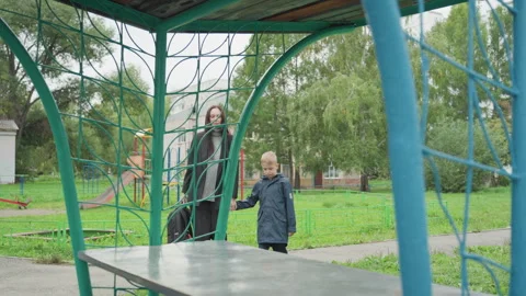 Child walking with guardian through park. Youth accompanied by guardian passing Stock Footage 335302952