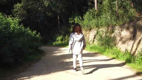 Child walking through a forest or a park with green leaves Stock Footage 134837326
