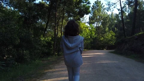 Child walking through a forest or a park with green leaves Stock Footage 134837364