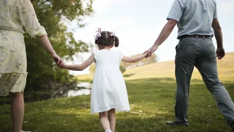 The child walks along with the parents, bouncing. Mother, father and daughter Stock Footage 235370392