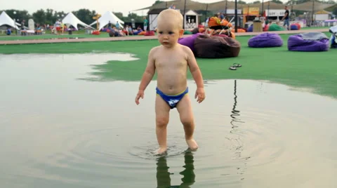 A Child Walks Barefoot Through a Puddle Stock Footage 64764673