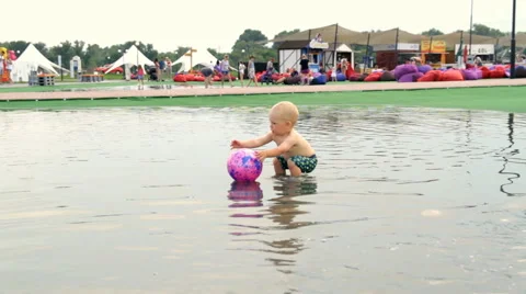 A Child Walks Barefoot Through a Puddle Stock Footage 64764996