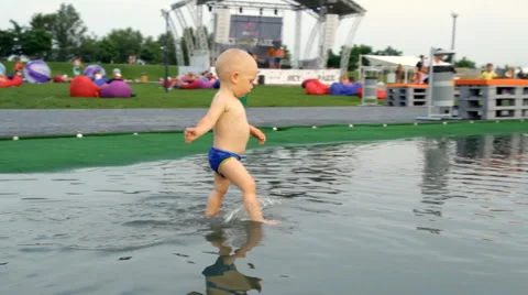 A Child Walks Barefoot Through a Puddle Stock Footage 64767167
