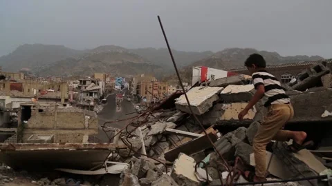A child walks between destroyed homes in Yemen Stock Footage 148659357