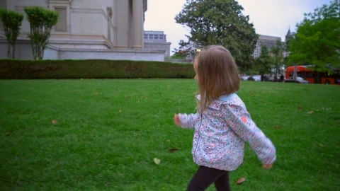 A child walks through the grass along a lawn in a big city. Overcast in Washingt Stock Footage 101033371