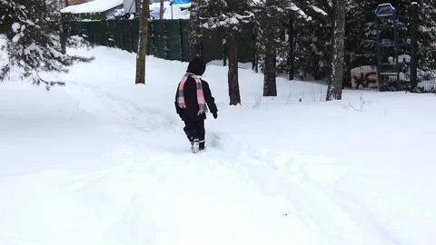 Child walks through snowy path in forest during winter day Stock Footage 328249040