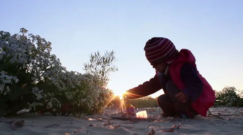 A child with warm hat playing on the beach at sunset time 動画素材 51370373