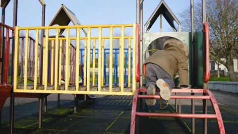 A child in a warm jacket climbs the stairs to the children's slide Stock Footage 234110993