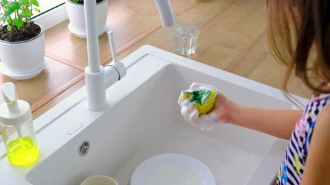 The child washes the dishes in the kitchen. Selective focus. Stock Footage 168664643