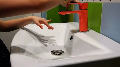 A child washes his hands under an orange mixer Stock Footage 77598109