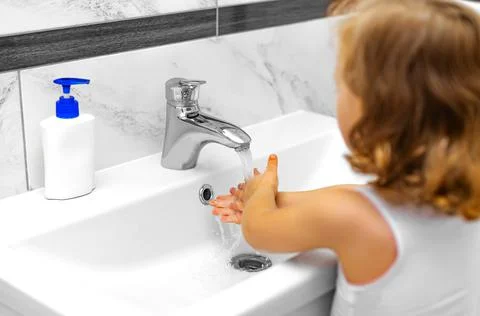 The child washes his hands under the tap. Stock Photos