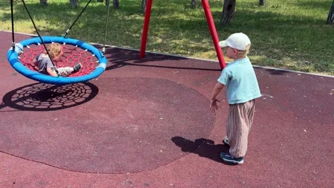 Child watching basket swing move at playground. Childhood during outdoor play Stock Footage 338055167