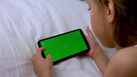 The child is watching a mobile phone in bed. Chromed green screen. Stock Footage 236945079