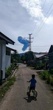 Child Watching Mount Marapi Eruption While Riding Bicycle Stock-Fotos