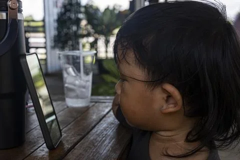 Child Watching Smartphone At The Table Stock Photos