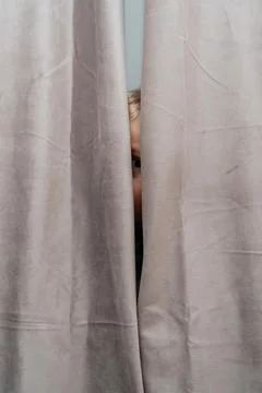 Child Watching Through Drapes Foto stock