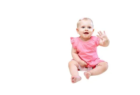 Child waves hand while sitting on the floor in a simple indoor space during Stock Photos