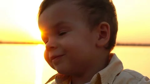 Child waving his head in the camera against the backdrop of the setting sun Stock Footage 75334702