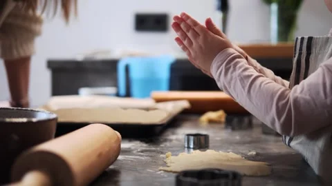 Child wearing an apron claps hands together over kitchen counter, removing dough Vidéo 289518916