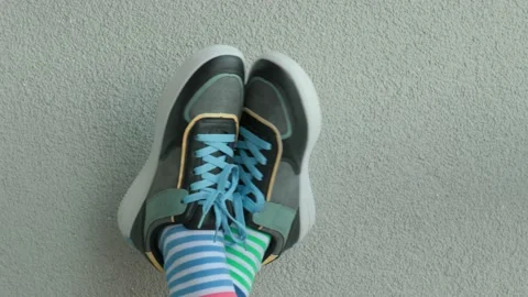 Child wearing different pair of socks. Kid legs up in mismatched socks on gray Stock Footage 202220328